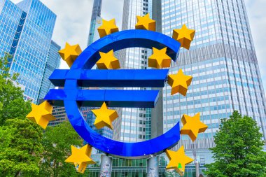 Frankfurt, Almanya - 10 Haziran 2025: Sarı yıldızlarla çevrili canlı mavi Euro tabela heykeli, Frankfurt 'un finans bölgesinde çağdaş gökdelenlere karşı gün ışığında hazırlanıyor.