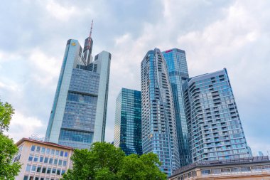 Frankfurt, Almanya - 10 Haziran 2025: Frankfurt 'un Commerzbank Kulesi ve Dörtlü projesinden modern gökdelenlerle olan gökdelenlerin çağdaş mimari ve kentsel tasarımı dramatik bir görünümü.