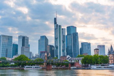 Frankfurt, Almanya - 10 Haziran 2025: Frankfurt 'un modern ufuk çizgisi manzarası, şehrin finans bölgesinin altını çizerek, bulutlu bir gökyüzünün altında ana nehir boyunca yüksek binalar sergiliyor..