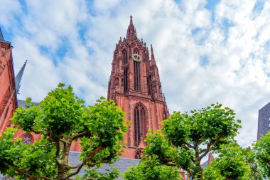 Saint Bartholomew İmparatorluk Katedrali 'nin ikonik Gotik mimarisi. Yeşillik ve Frankfurt, Almanya' da dramatik bir gökyüzü tarafından çerçevelenmiş..