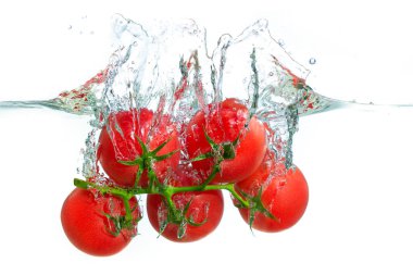 Canlı kırmızı domateslerin temiz suya sıçrayıp dinamik kabarcıklar ve dalgalanmalar oluşturduğu yakın plan görüntüsü..