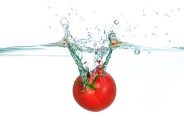 Canlı kırmızı domates, kabarcıklar ve damlacıklarla çevrili berrak suda dinamik bir sıçrama yaparak enerjik ve taze bir atmosfer yaratıyor..