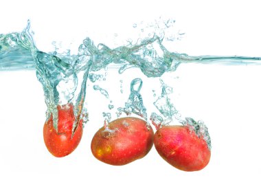 Taze kırmızı patateslerin yakın plan görüntüsü canlı kabarcıklarla dinamik sıçramalar yaratarak tazeliği ve canlılığı vurguluyor..