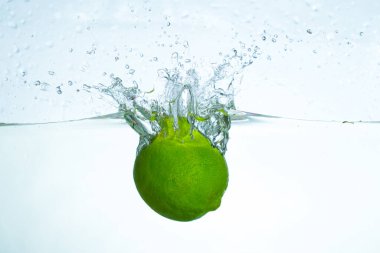 Limonun berrak suya sıçrayıp parlak ve ferahlatıcı bir atmosferle kabarcıklar ve dalgalanmalar oluşturduğu yakın çekim görüntüsü..