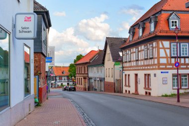 Rossdorf, Almanya - 23 Haziran 2025: Rossdorf 'ta tarihi bir Alman mimarisi ve parçalı bulutlu bir gökyüzü altında sakin bir atmosfer içeren tuhaf bir caddenin manzarası.