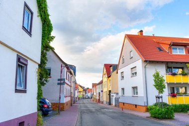 Rossdorf, Almanya - 23 Haziran 2025: Rossdorf, Almanya 'da renkli evlerle dolu büyüleyici bir yerleşim caddesi, bulutlu bir gökyüzünün arka planına karşı geleneksel mimariyi gözler önüne seriyor.