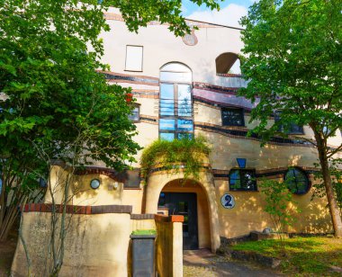 Benzersiz kıvrımlara ve canlı renklere sahip Waldspirale konut kompleksinin mimari ayrıntıları Almanya 'nın Darmstadt kentindeki yemyeşil ağaçların arka planına kurulmuştur..