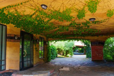 Yeşilliklerle bezenmiş Waldspirale konut kompleksinin girişi, eşsiz bir mimari tasarım ve canlı renkler içeriyor..