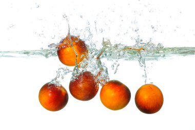 Domateslerin berrak suda su sıçratması, dinamik kabarcıklar ve dalgalanmalar yaratması, meyvelerin taze ve canlı renklerini vurguluyor..