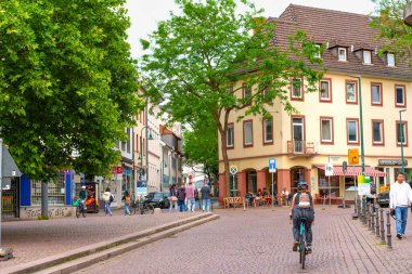 Darmstadt, Almanya - 5 Haziran 2025: Darmstadt 'ta hayat dolu bir günde kafelerin ve ağaçların önünden geçen bir bisikletlinin görüntüsü.