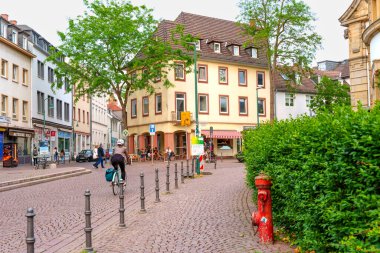 Darmstadt, Almanya - 5 Haziran 2025: Bisikletçi Darmstadt, Almanya 'daki dükkanlar ve yeşilliklerle kaplı antika bir kaldırım taşı caddesinde geziniyor..