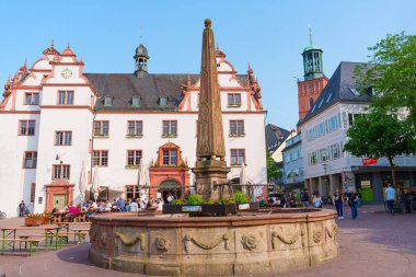Darmstadt, Almanya - 5 Haziran 2025: Darmstadt 'ta güneşli bir günün keyfini çıkaran dekoratif bir çeşme, tarihi binalar ve canlı yayaların yer aldığı büyüleyici kasaba meydanı.