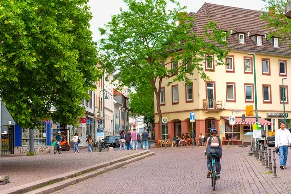 Darmstadt, Almanya - 5 Haziran 2025: Darmstadt 'ta hayat dolu bir günde kafelerin ve ağaçların önünden geçen bir bisikletlinin görüntüsü.
