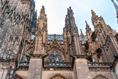 Köln, Almanya - 15 Haziran 2025: Köln Katedrali 'nin karmaşık mimari ayrıntıları, bulutlu bir gökyüzüne karşı taş ve kuleler sergilenmesi, Gotik tasarımın ihtişamını vurgulamak.