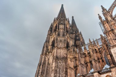 Köln, Almanya - 15 Haziran 2025: Köln Katedrali 'nin karanlık çöktüğünde karamsar bir gökyüzüne yükselen Gotik mimari detayları, karmaşık taş işçiliğini ve kuleleri vurguladı.