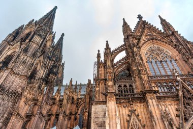 Köln, Almanya - 15 Haziran 2025: Cologne Katedral Kulesi 'nin karanlık çöktüğünde karamsar bir gökyüzüne karşı yükselen Gotik mimari detaylarının dramatik düşük açılı görüntüsü.