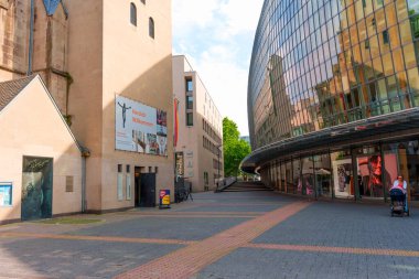 Köln, Almanya - 15 Haziran 2025: Gündüz vakti Almanya 'nın Köln kentindeki tarihi bir yapının yanında modern cam cephe içeren karışık mimari tarzlar.