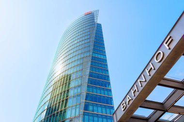 Berlin, Almanya - 16 Ağustos 2025: Sersemletici BahnTower manzarası, Deutsche Bahn karargahı, parlak mavi gökyüzü altında parlak cam tasarımı ve canlı kentsel çevre.