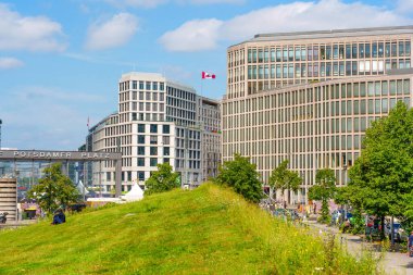 Berlin, Almanya - 16 Ağustos 2025: Berlinde dinamik bir kentsel manzara yaratan yemyeşil ve canlı mavi gökyüzü tarafından vurgulanan Potsdamer Platz 'daki çağdaş binalar.