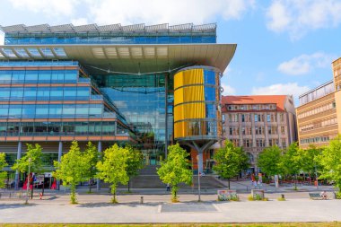 Berlin, Almanya - 16 Ağustos 2025: Linkstrasse 6 binasının çarpıcı modern tasarımı, cam cephe, sarı silindirik element ve kentsel Berlin 'de yeşil peyzaj.