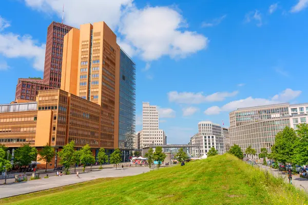 Berlin, Almanya - 16 Ağustos 2025: Kollhoff Kulesi ve Atrium Kulesi, canlı yeşil alan, kentsel manzara, Berlin, Almanya 'da güneşli bir gün.