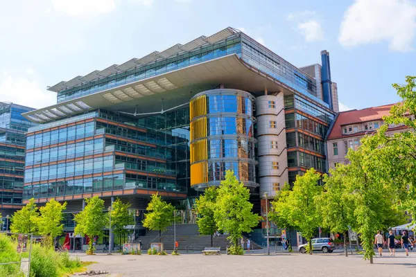 Berlin, Almanya - 16 Ağustos 2025: Berlin 'de Linkstrasse 6' nın mimari yapısı cam ve metal cephelerin bulunduğu yemyeşil ve mavi gökyüzü.