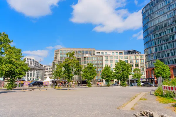 Berlin, Almanya - 16 Ağustos 2025: Çağdaş binalar, bereketli ağaçlar ve Berlin 'de berrak mavi bir gökyüzünün yer aldığı canlı kentsel manzara, doğa ve şehir hayatının karışımını gözler önüne seriyor..