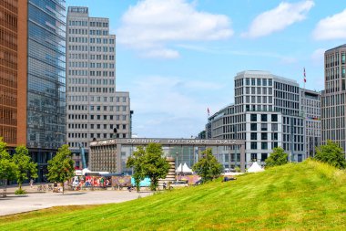 Berlin, Almanya - 16 Ağustos 2025: Potsdamer Platz 'ın canlı şehir manzarası modern mimari, yeşil alanlar ve mavi gökyüzü altında canlı bir atmosfer.
