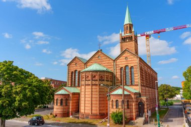 Berlin, Almanya - 16 Ağustos 2025: Berlin 'deki St. Matthew Kilisesi' nin mimari görüşü, canlı bir gökyüzüne karşı belirgin kırmızı tuğla cephesi ve yeşil çatısını vurguluyor.
