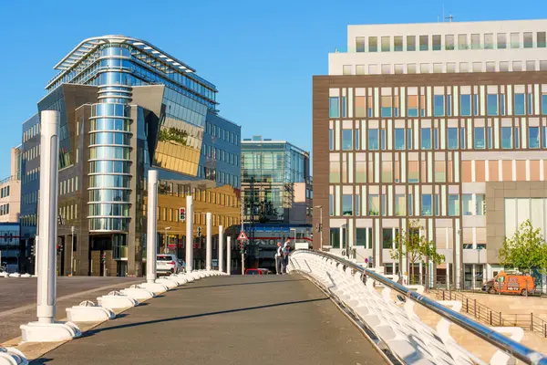 Berlin, Almanya - 16 Ağustos 2025: Canlı kentsel ortamda cam cepheli ve yaya köprüsüne sahip çağdaş binalar.