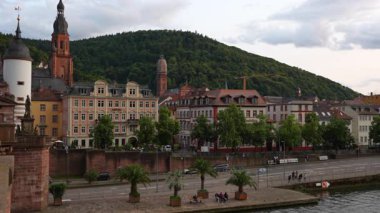 Heidelberg, Almanya - 21 Haziran 2025: Iconic Old Bridge ve Heidelberg 'deki Karl Theodor Gate, sergilenen evler ve canlı yeşil tepeler.