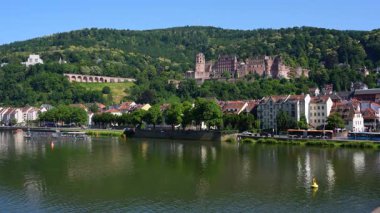 Heidelberg, Almanya - 21 Haziran 2025: Heidelberg Şatosu 'nun bir tepe üzerindeki manzarası, sahil boyunca büyüleyici evler bulunan Neckar Nehri' ne yansıyor.