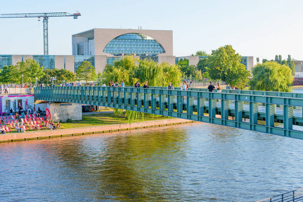 Берлин, Германия - 16 августа 2025 года: Пешеходы, пересекающие мост через реку Шпрее, на фоне городской жизни и развлекательных мероприятий.