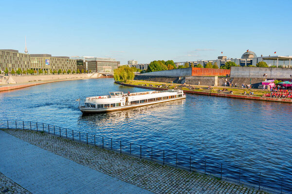 Берлин, Германия - 16 августа 2025 года: Круизные лодки, плывущие по реке Шпрее, подчеркивают прекрасное взаимодействие между рекой и городским ландшафтом Берлина.