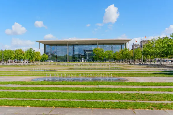 Berlin, Almanya - 17 Ağustos 2025: Berlin 'deki çağdaş bir parlamento binasının önündeki yemyeşil bir parkta fıskiyeler kuruyor.