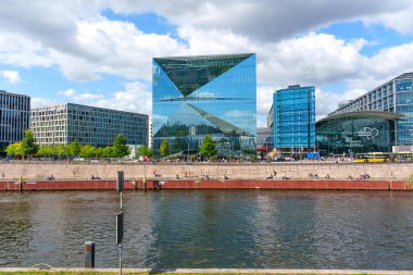 Berlin, Almanya - 17 Ağustos 2025: Berlin 'in merkez tren istasyonu yakınlarındaki gökyüzü ve nehri yansıtan çağdaş cam binalar, kentsel gelişim ve tasarım sergiliyor.