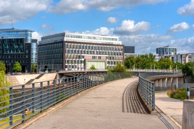 Berlin, Almanya - 17 Ağustos 2025: Berlin 'deki Federal Basın Konferansı' nın çağdaş mimari tasarımı, mavi gökyüzü altında manzaralı bir yol ve canlı bir yeşillik tarafından çerçevelenmiştir..