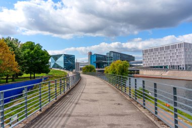 Berlin, Almanya - 17 Ağustos 2025: Berlin 'de çağdaş binalar ve yemyeşil yeşilliklerin yer aldığı Spree Nehri' nin yanındaki patika.