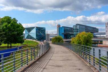 Berlin, Almanya - 17 Ağustos 2025: Küp Berlin 'in mimari görünümü ve çağdaş binalar, yeşil manzaralar ve açık mavi gökyüzünün yer aldığı ana tren istasyonu.