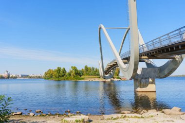 Kyiv 'deki dalgalı yaya köprüsünün çarpıcı geniş açılı görüntüsü, suyun üzerinde zarif bir şekilde kavis çiziyor..