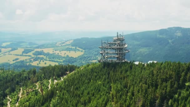ドルニ モラヴァのスカイウォークタワーと木製の湾曲した展望デッキ 夏の晴れた日に緑豊かな木々に覆われた高い山のピークの魅力空中風景 — ストック動画