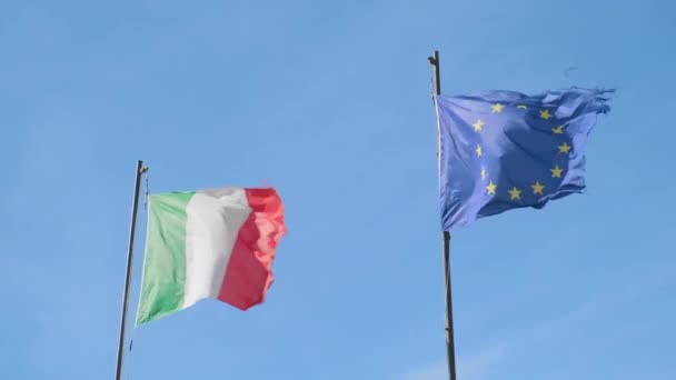 意大利和欧盟的国旗在大风中飘扬 在无云蓝天的低角射击中 旗杆上的风旗扭动迅速 — 图库视频影像