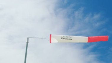 ORTISEI, İtalya - 10 Eylül 2022: direğin üzerindeki beyaz ve kırmızı rüzgar yelkeni rüzgarın yön ve gücünü gösteriyor. Beyaz bulutlu mavi gökyüzüne karşı sinyal renkleri rüzgarı.