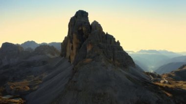 Güneş, kayalık dağ siluetinin zirvesinden yükseliyor. Dolomite Alpleri 'nin açık gökyüzü altındaki manzarası. Gündoğumunda Tre Cime di Lavaredo arka taraftaki hava manzarası aydınlandı.