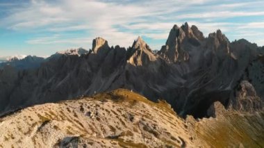 Yeni evliler gün batımında dağın tepesinde Cliff 'e karşı düğün fotoğrafları ve videolar çekiyorlar. Lavaredo 'nun üç tepesi mavi gökyüzü manzarasının altında.