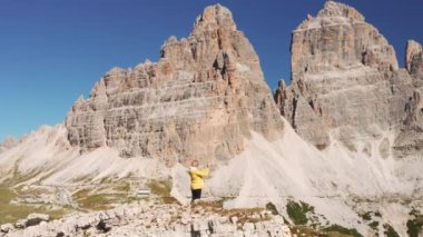 Sarışın kadın, kayalık dağlara karşı akıllı telefondan selfie çekiyor. Dişi gezgin, Tre Cime di Lavaredo yakınlarındaki dağları teftiş eder.