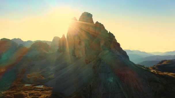 日の出のTre Cime Lavaredoの山の風景 バックライトで澄んだ空の航空ビューの下でアルプスのロッキー山脈と広い高地の谷 — ストック動画