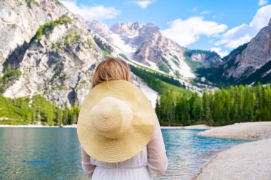 Beyaz elbiseli ve şapkalı genç kadın Braies ve Dolomites Alpleri, İtalya 'nın manzaralı gölünün tadını çıkarıyor..