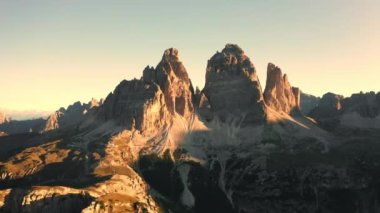 Gün doğumunda Tre Cime di Lavaredo 'nun Rocky tepeleri. Geniş tepe kanyonları ve kıvrımlı yolları açık gökyüzü manzarasının altında olan vadi manzarası.
