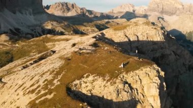 Yeni evliler, Lavaredo 'nun Üç Tepesi' ndeki kayalık kayalıklara karşı dağda film ve fotoğraf çekiyorlar. Gün batımında gökyüzü manzaralı görkemli dağ sıraları